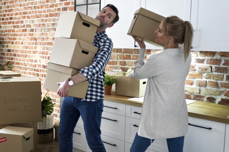 Couple during moving out takes cardboard boxes